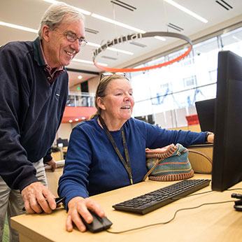 Two people looking at a computer. Links to Gifts from Retirement Plans